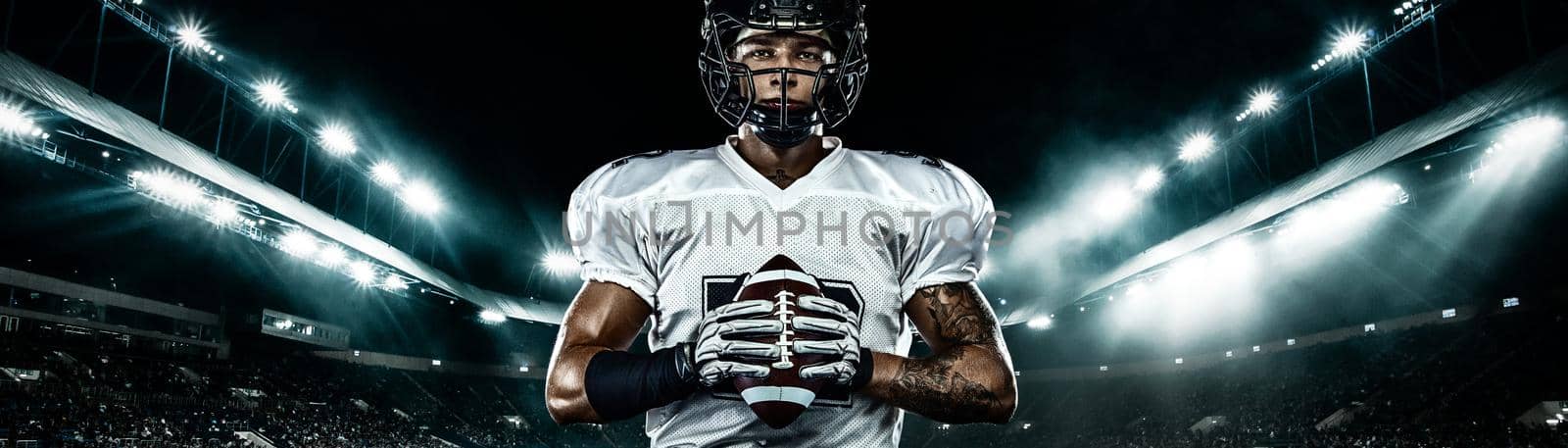American football player, athlete sportsman in red helmet on stadium background. Sport and motivation wallpaper. Wide photo. by MikeOrlov