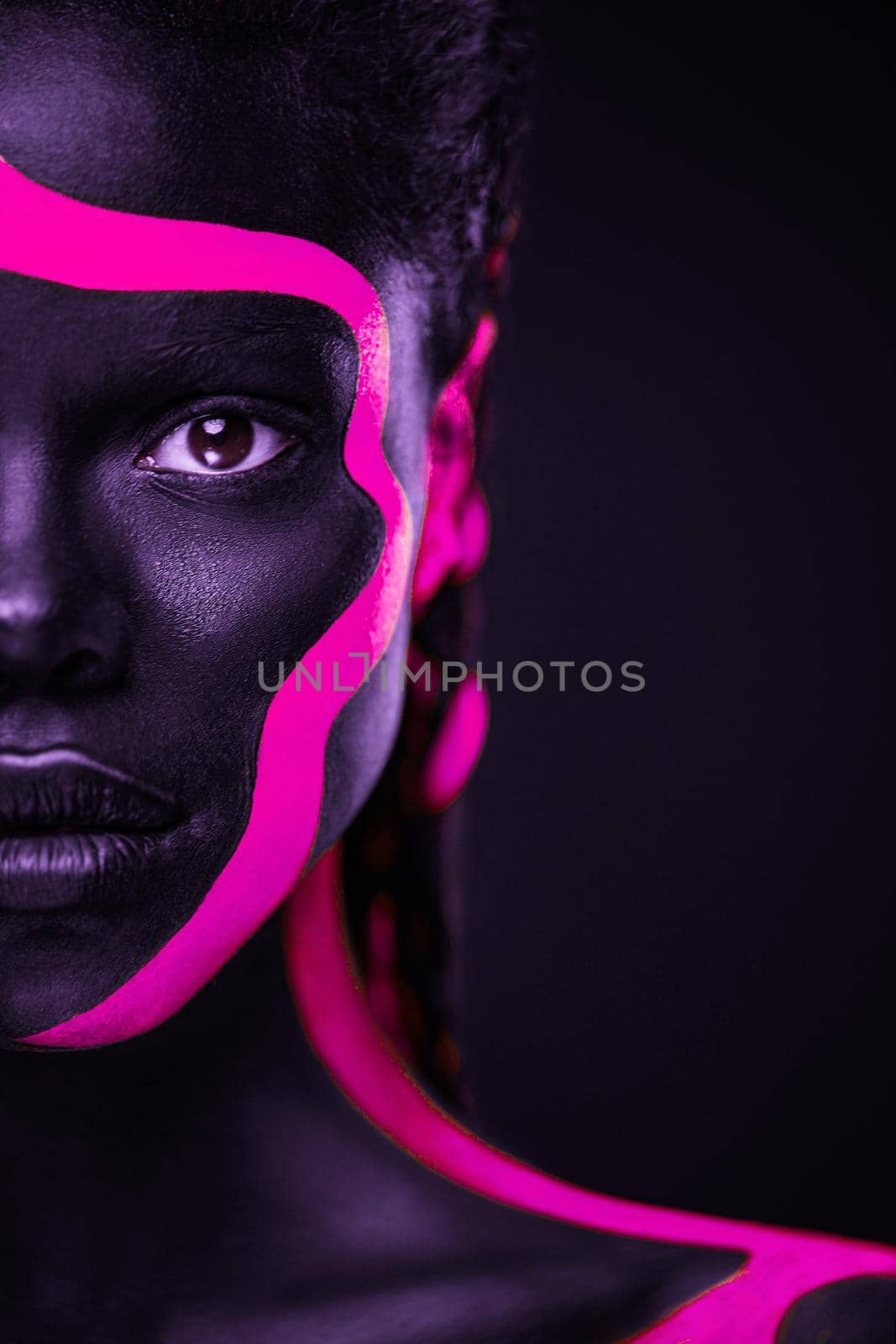 Neon colors. Pink and black body paint. Woman with face art. Young girl with colorful bodypaint. An amazing afro american model with makeup