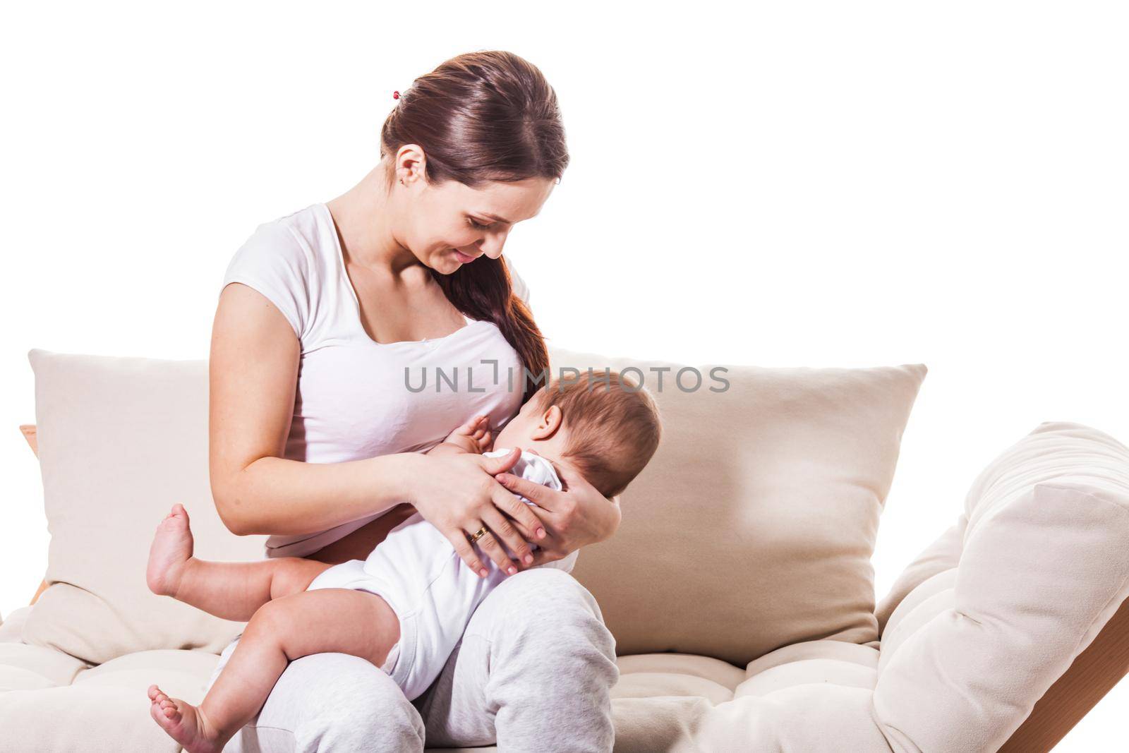 The young woman begins to breastfeed her baby while sitting on the couch