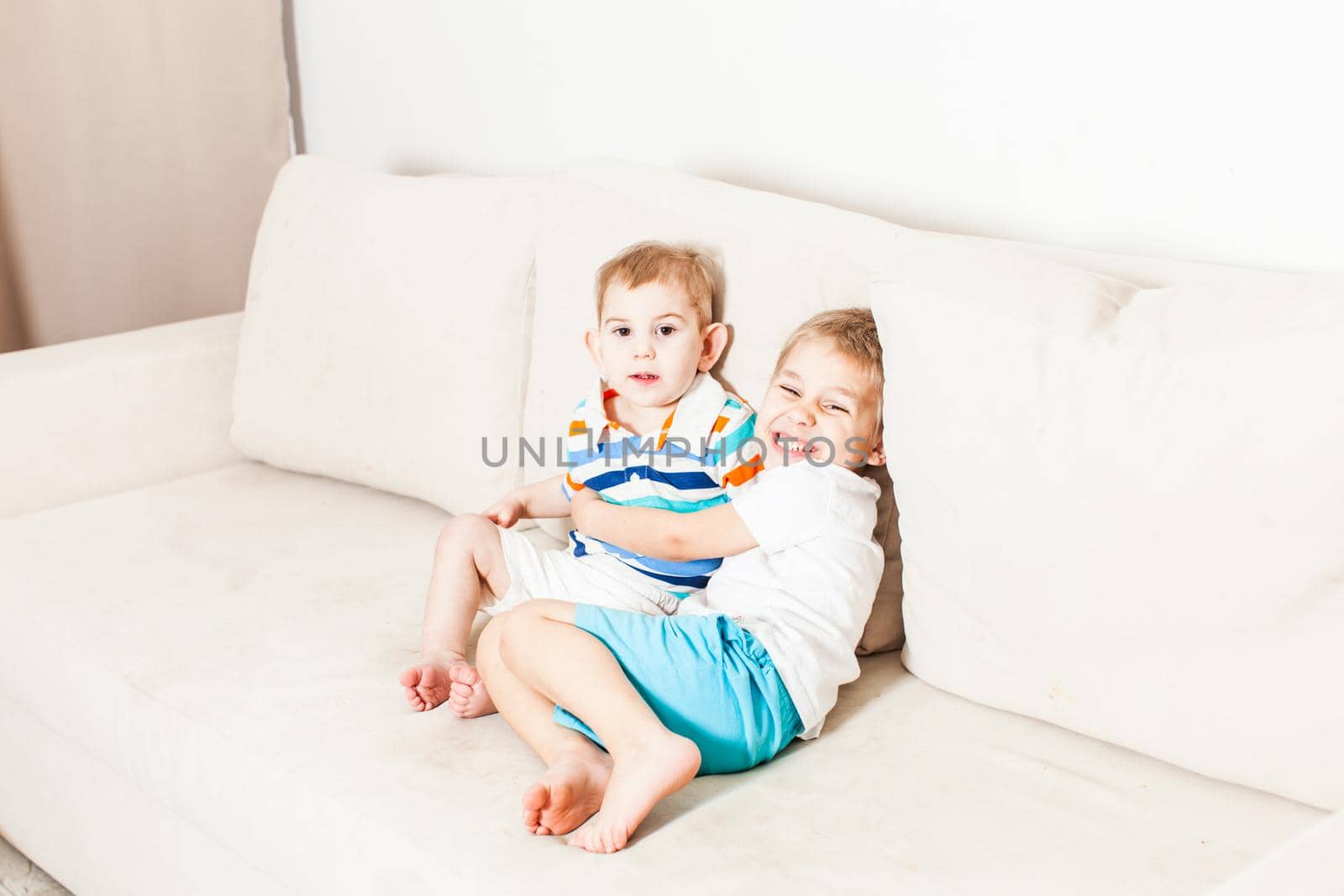 Two brothers hugging on the white couch