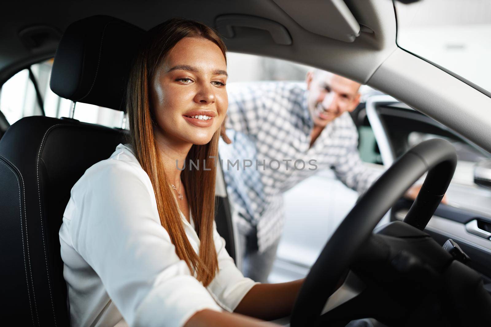 Young attractive woman looking for a new car in a car showroom