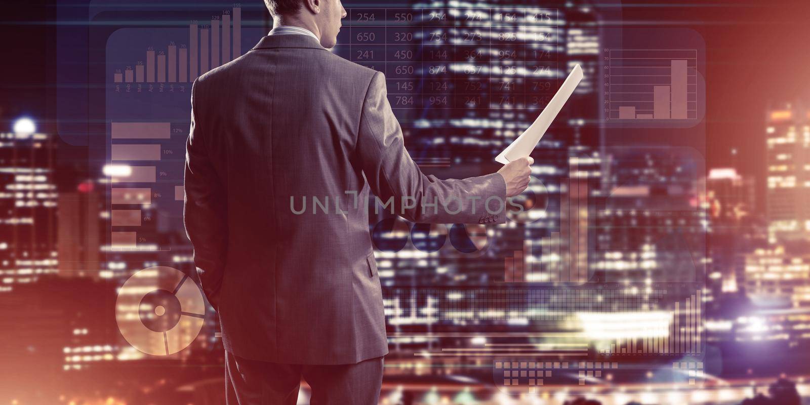 Rear view of businessman against virtual panel interface holding papers in hand