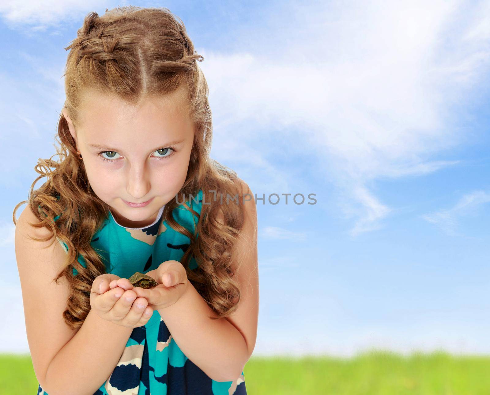Beautiful little girl holding hands the little turtle. Close-up.Summer white green blurred background.