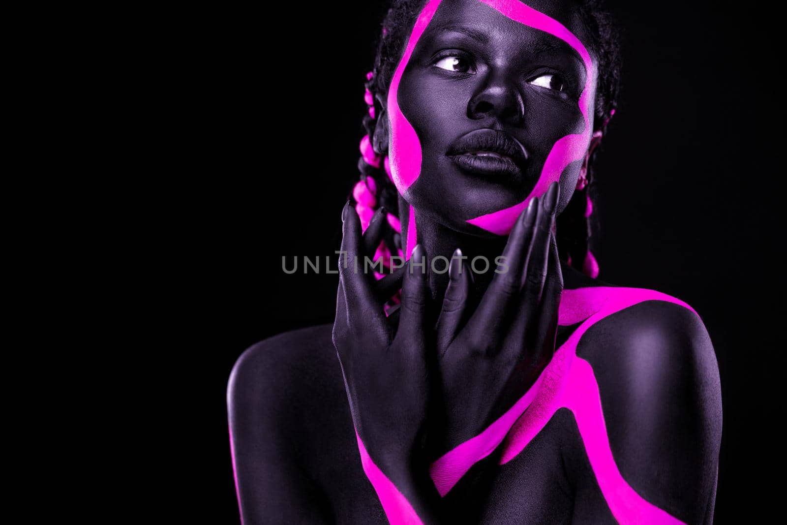 Neon colors. Pink and black body paint. Woman with face art. Young girl with colorful bodypaint. An amazing afro american model with makeup