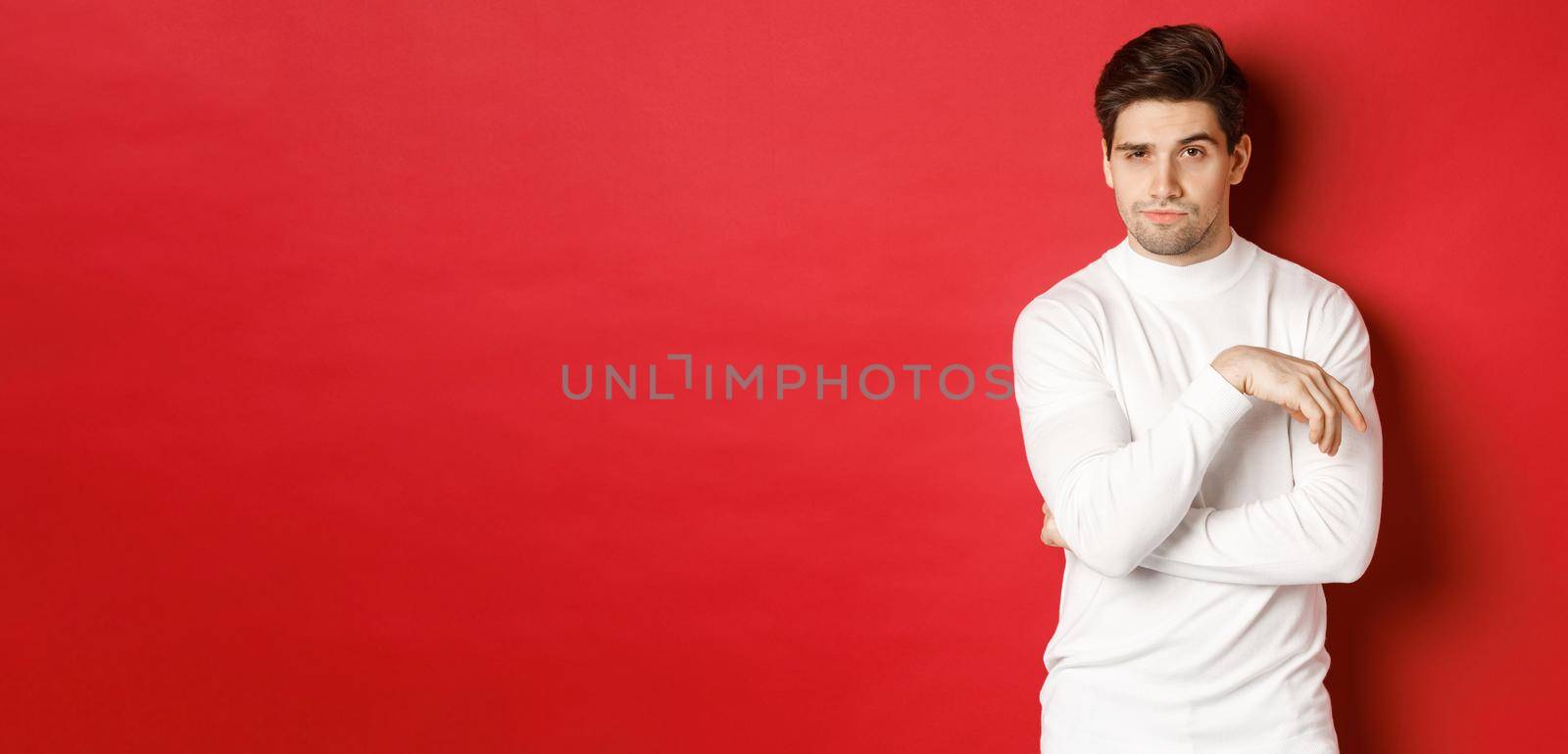 Image of sassy caucasian man in white sweater, looking thoughtful at camera, making choice, standing over red background by Benzoix