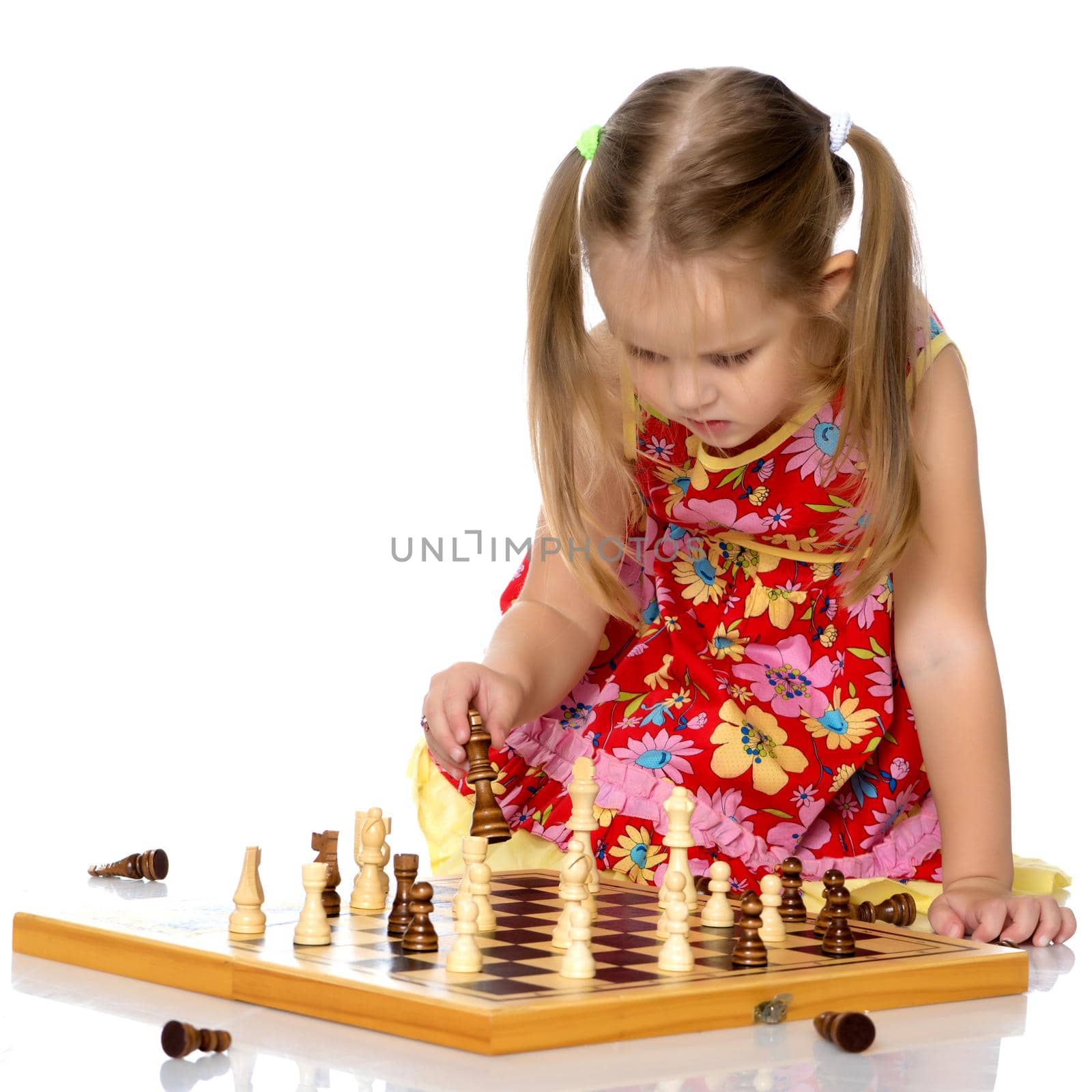 A little girl is playing chess. The concept of creative education of a child, training of thinking. Isolated on white background