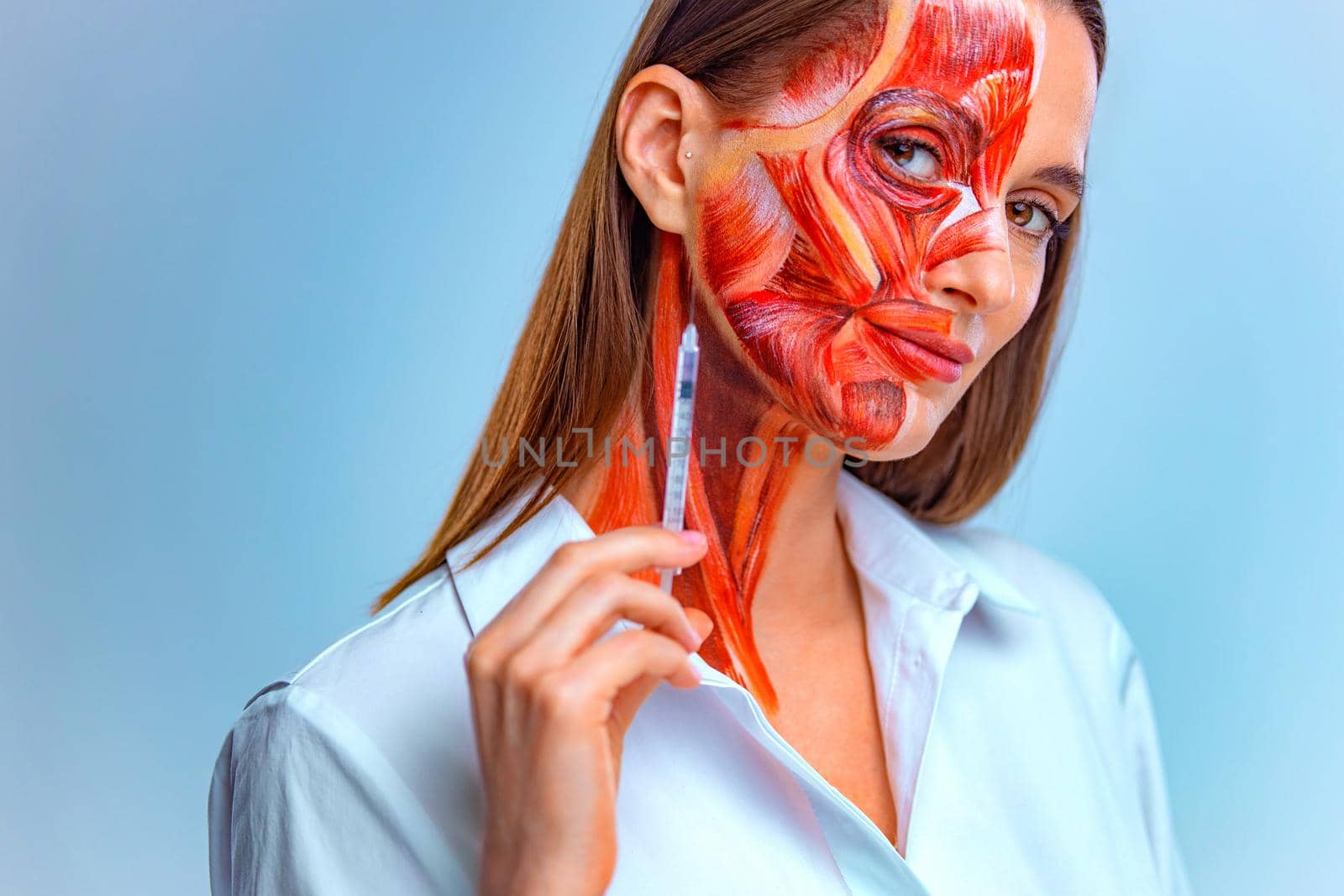 Cosmetic injection in the face. Young woman with half of face with muscles structure under skin. Model for medical training on a light background. by MikeOrlov