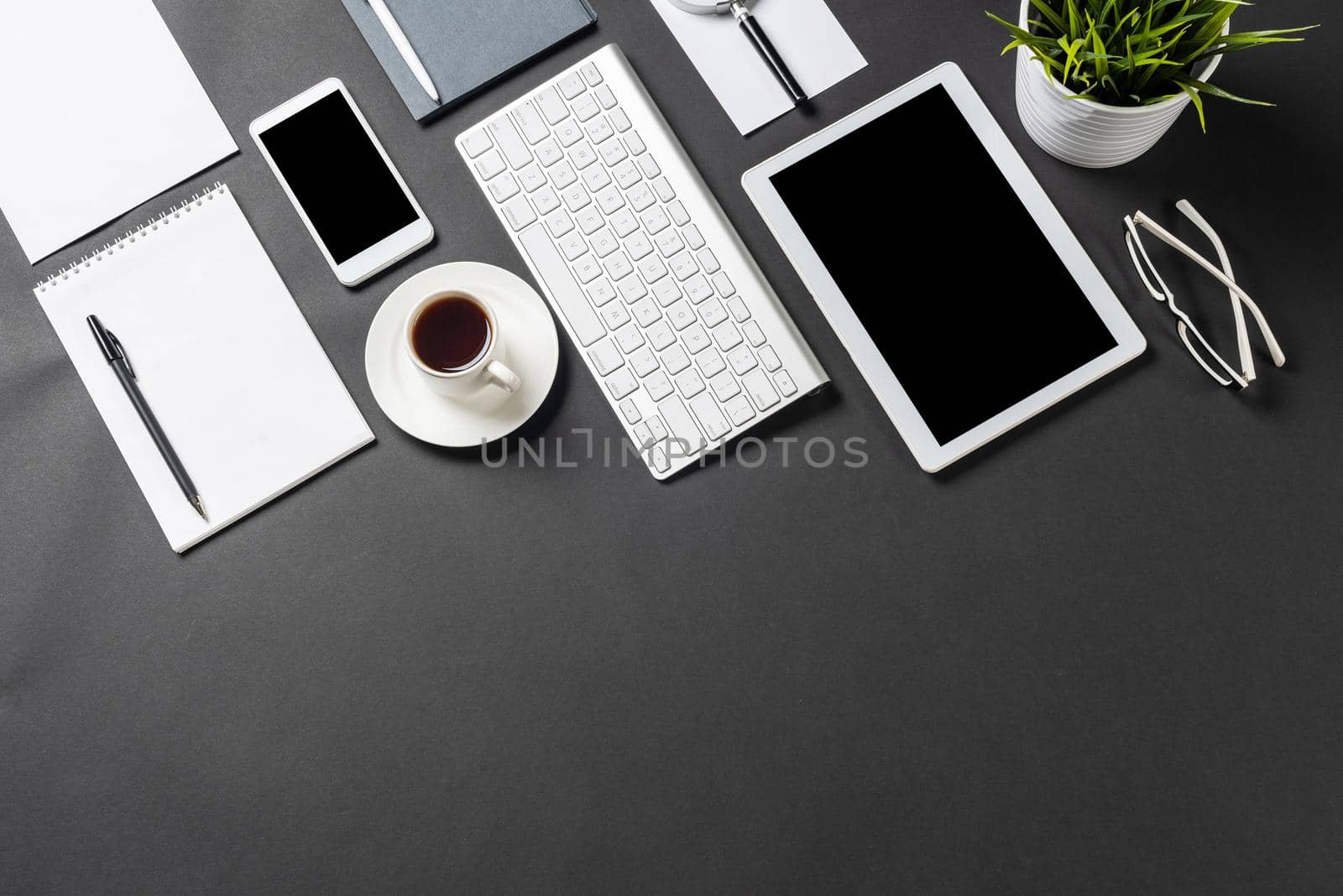 Top view of workplace with modern digital devices. Flat lay stylish design with black surface and copy space. Professional consulting, audit and accounting. Digital technology and mobile lifestyle.