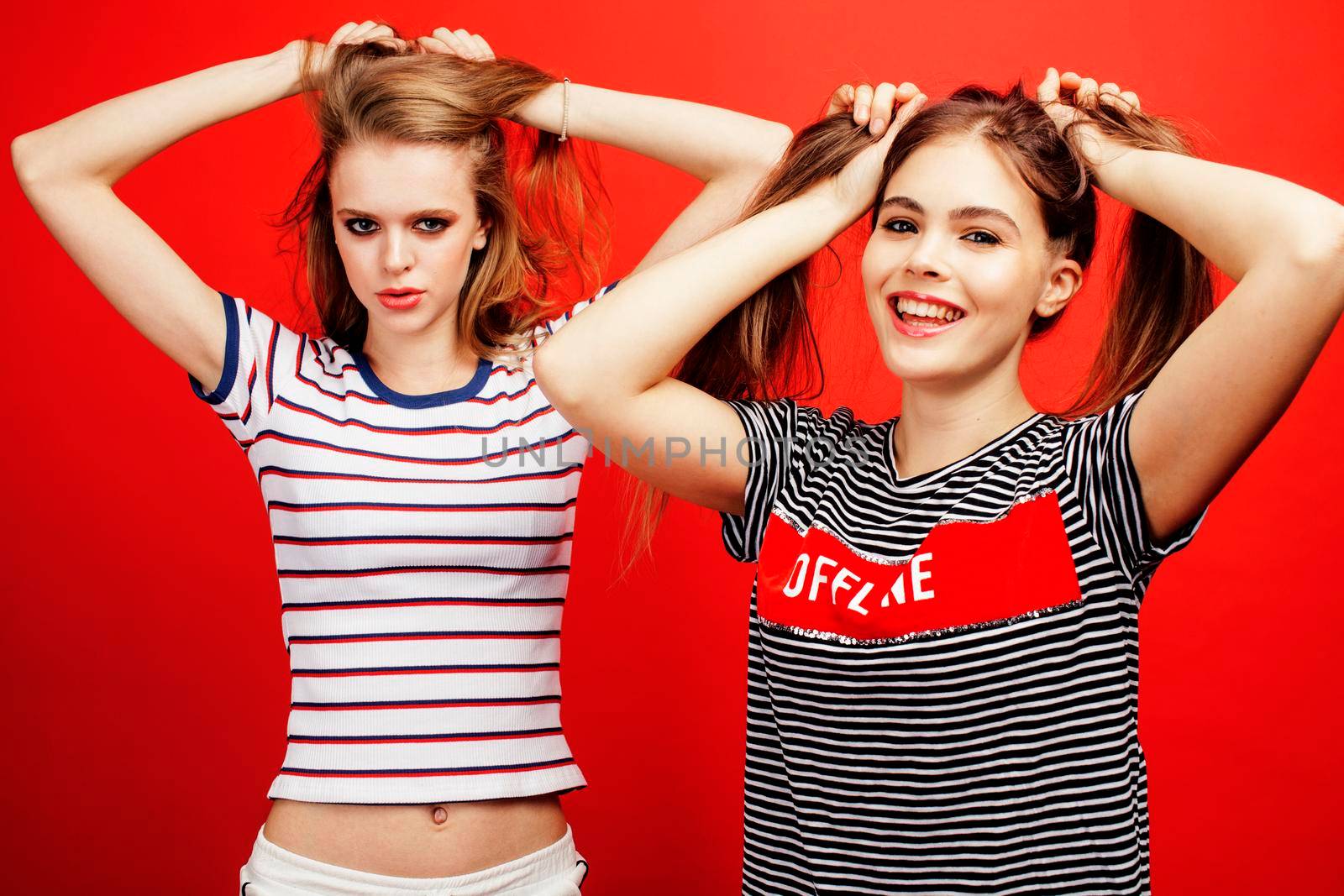 two best friends teenage girls together having fun, posing emotional on red background, besties happy smiling, lifestyle people concept close up