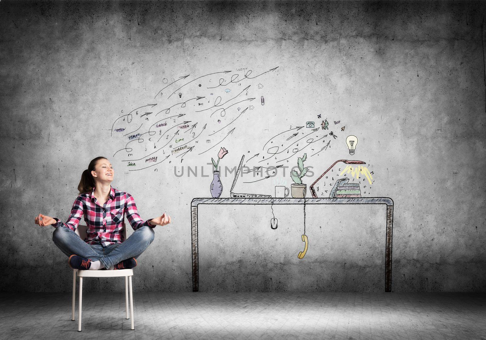 Young happy woman relaxing in room. Creative freelancer sitting in lotus pose on chair. Home workspace with computer on desk illustration on wall. Smiling girl doing yoga at home in leisure time.