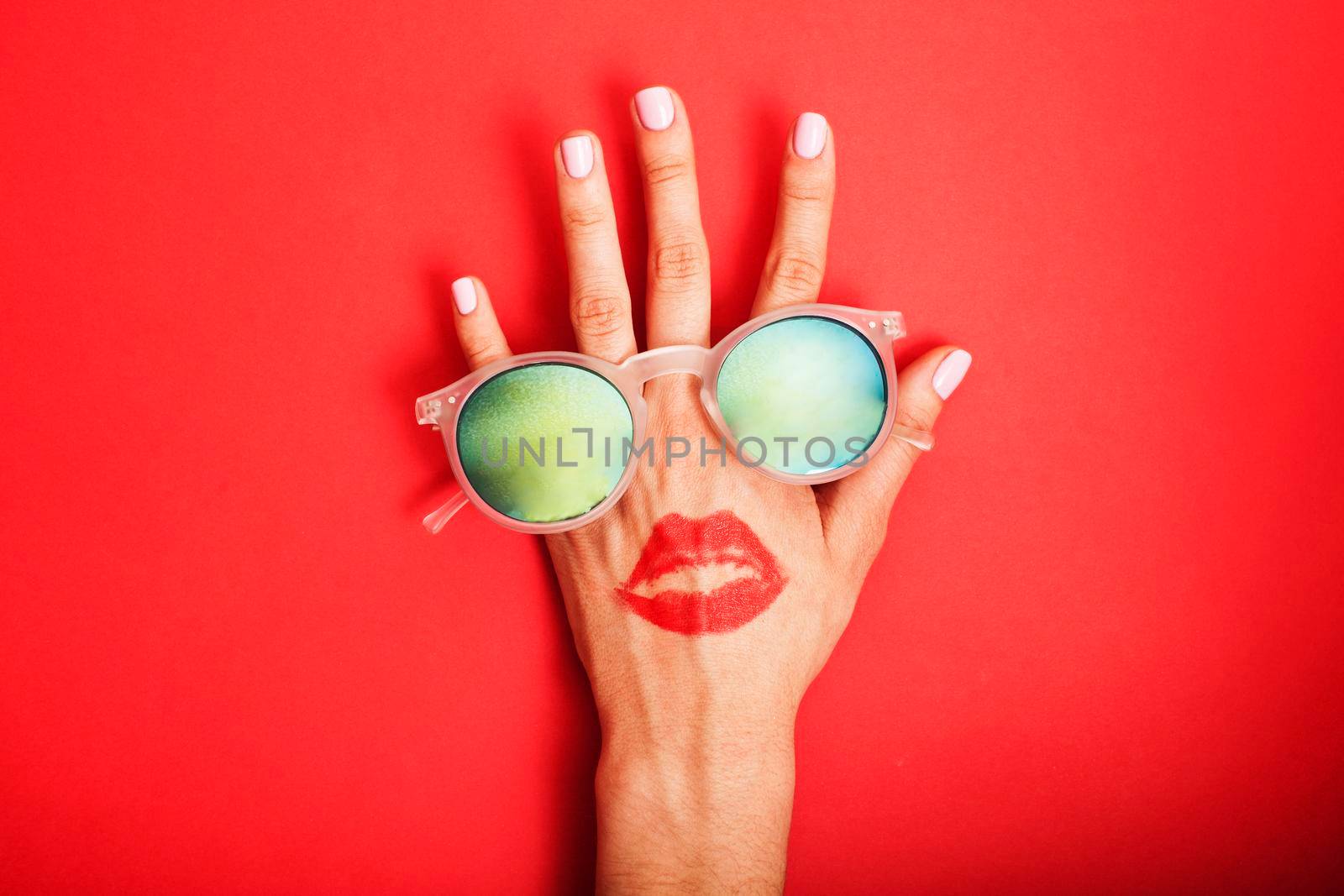 woman hand holding sunglasses on bright background, cosmetic summer vacation concept close up