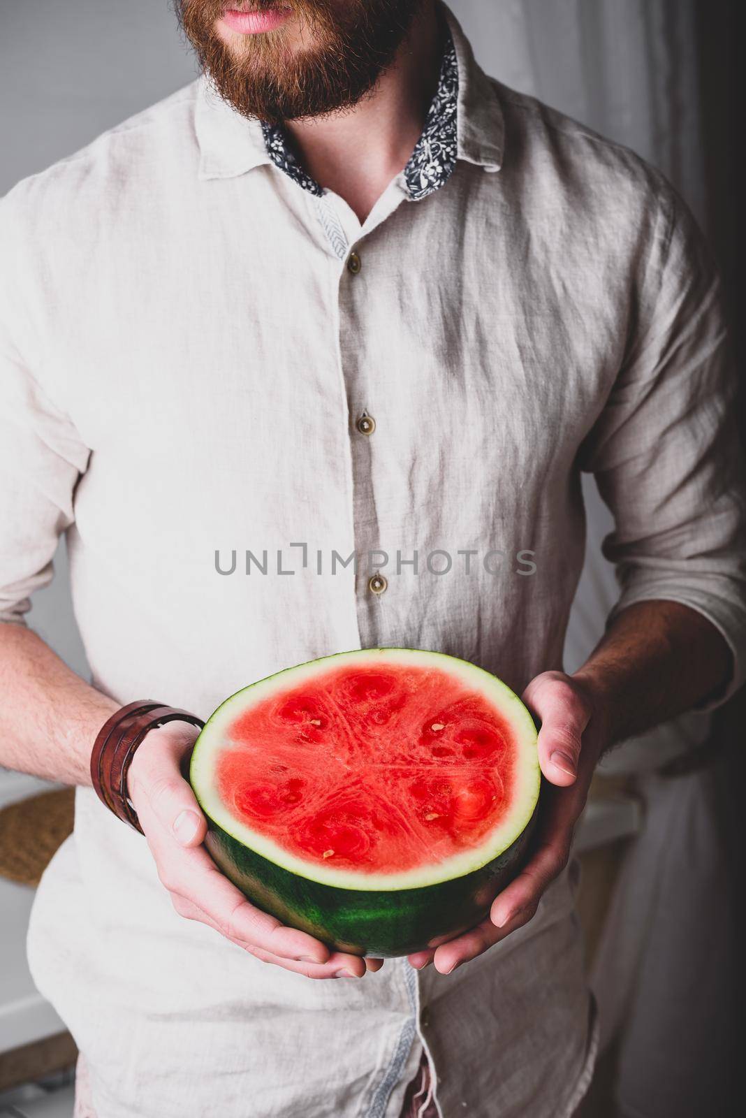Bearded man holds in hands half of red watermelon by Seva_blsv