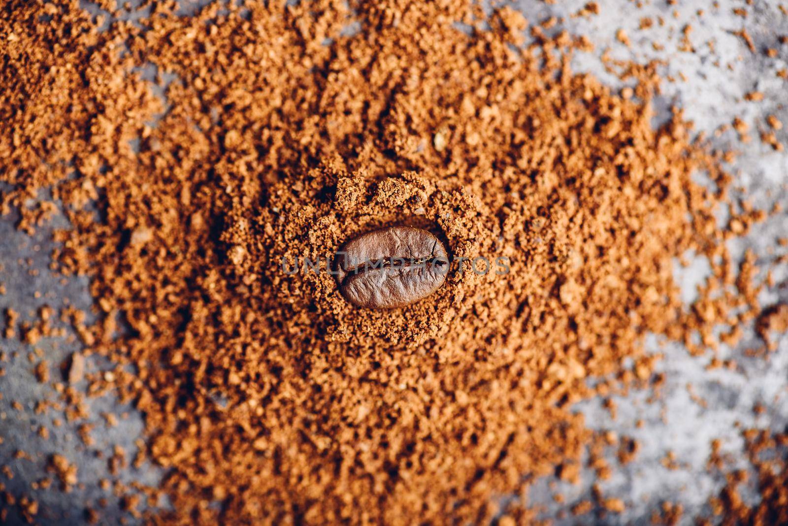 Fresh roasted coffee bean lays on heap of grinded coffee