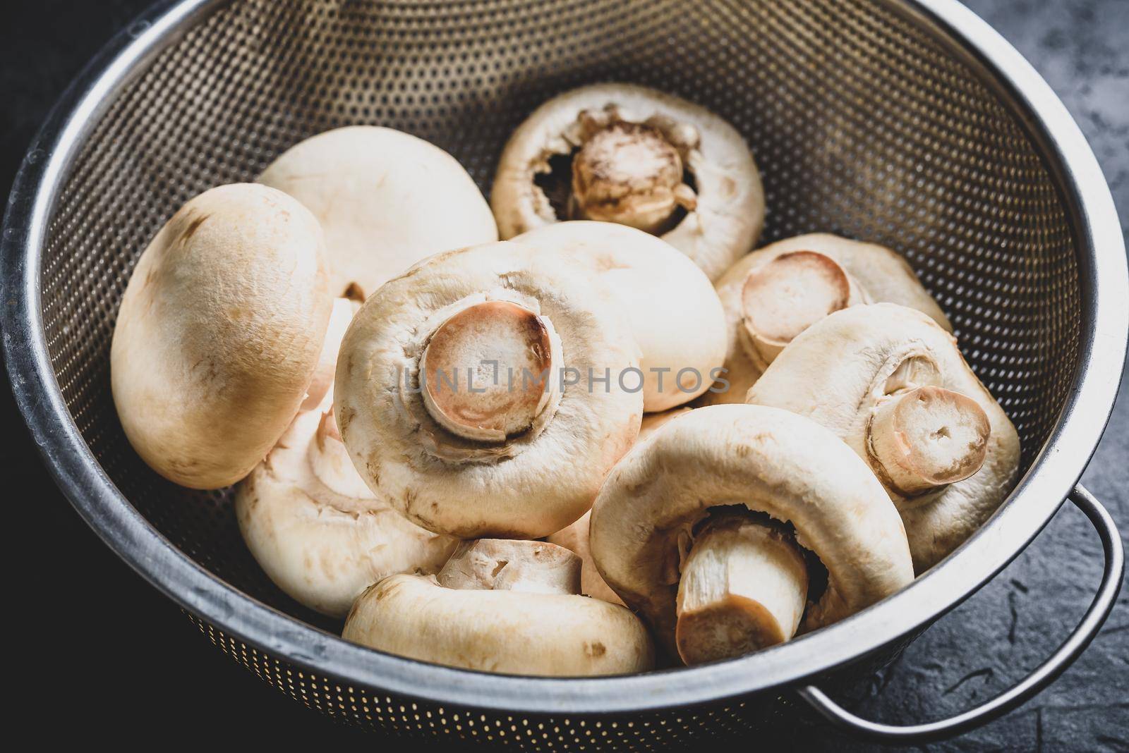Fresh white button mushrooms in metal colander