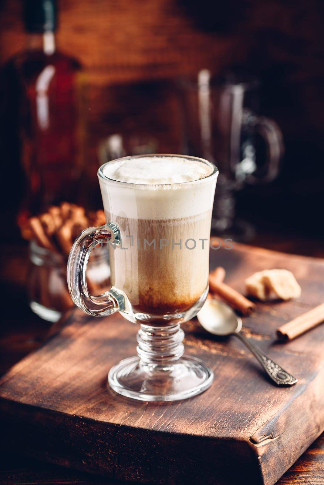 Coffee with Irish whiskey and whipped cream in glass on rustic wooden surface