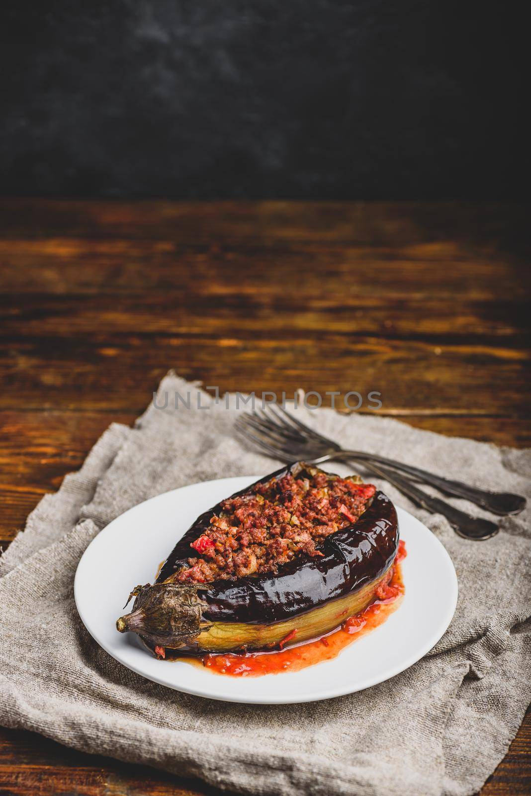 Baked eggplant stuffed with ground beef, tomatoes and spices on white plate. Traditional dish Karniyarik of turkish cuisine