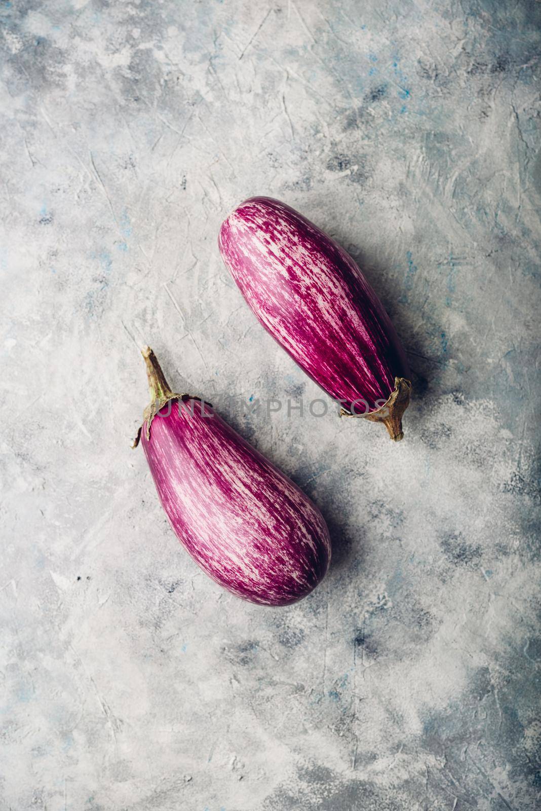 Two purple aubergines on light concrete background