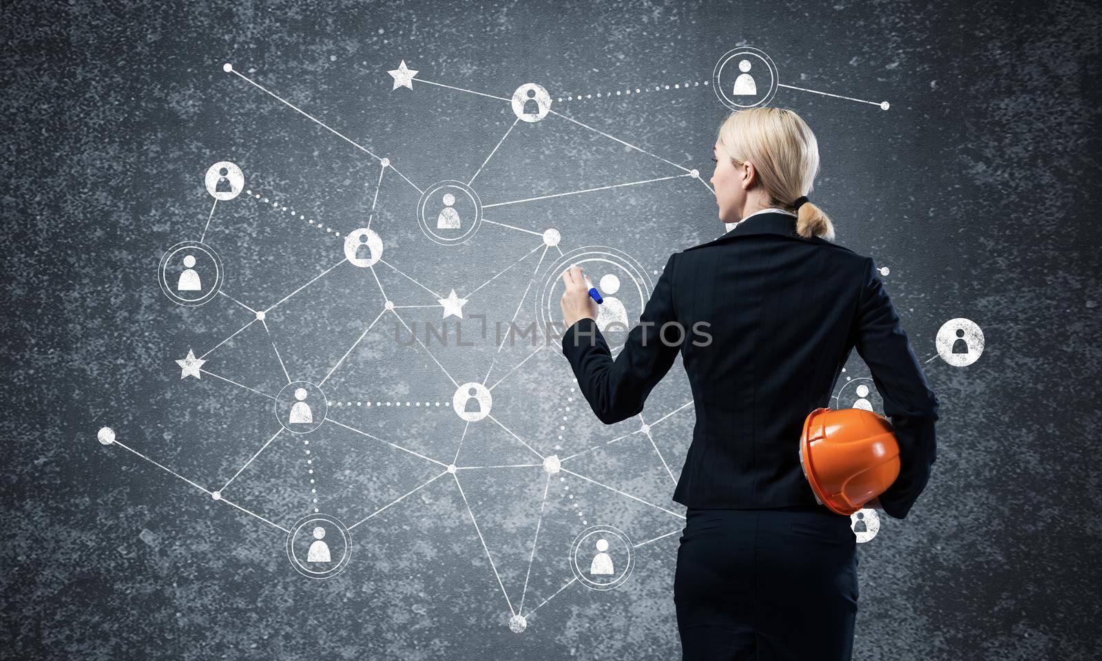Businesswoman pointing on abstract social network. Back view of woman headhunter in business suit and safety helmet. Social connection structure. Human resources recruitment and people networking.