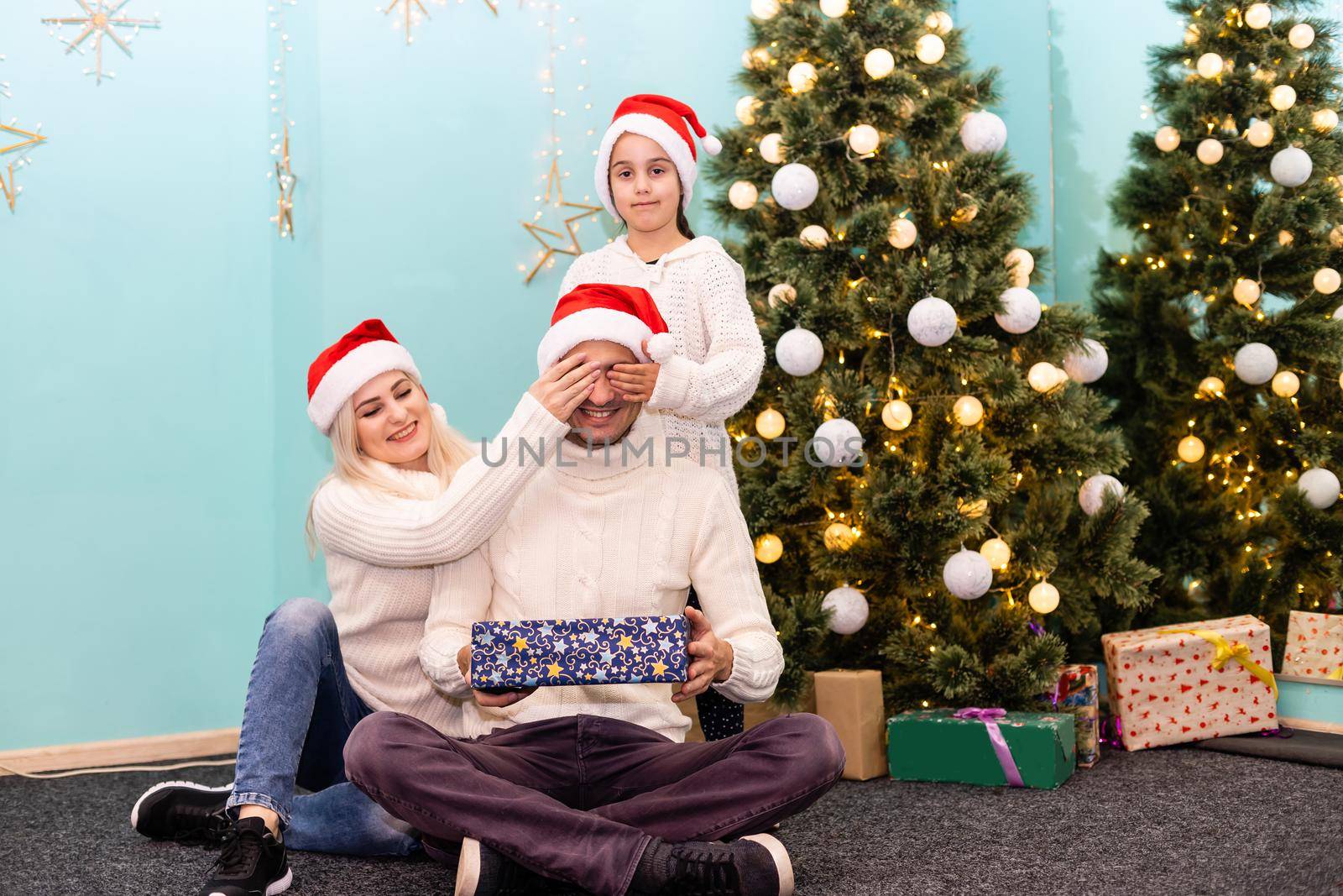 happy young family with one child holding christmas gift and smiling at camera