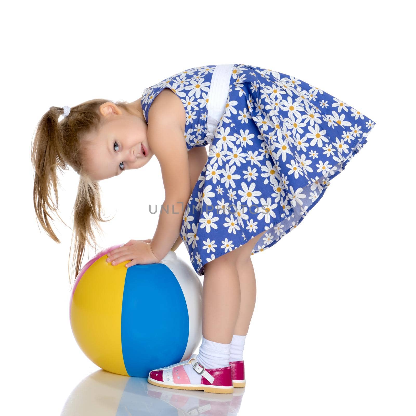 A nice little girl is playing with a big inflatable ball. The concept of a happy childhood, family recreation in nature, fitness and exercise. Isolated on white background.