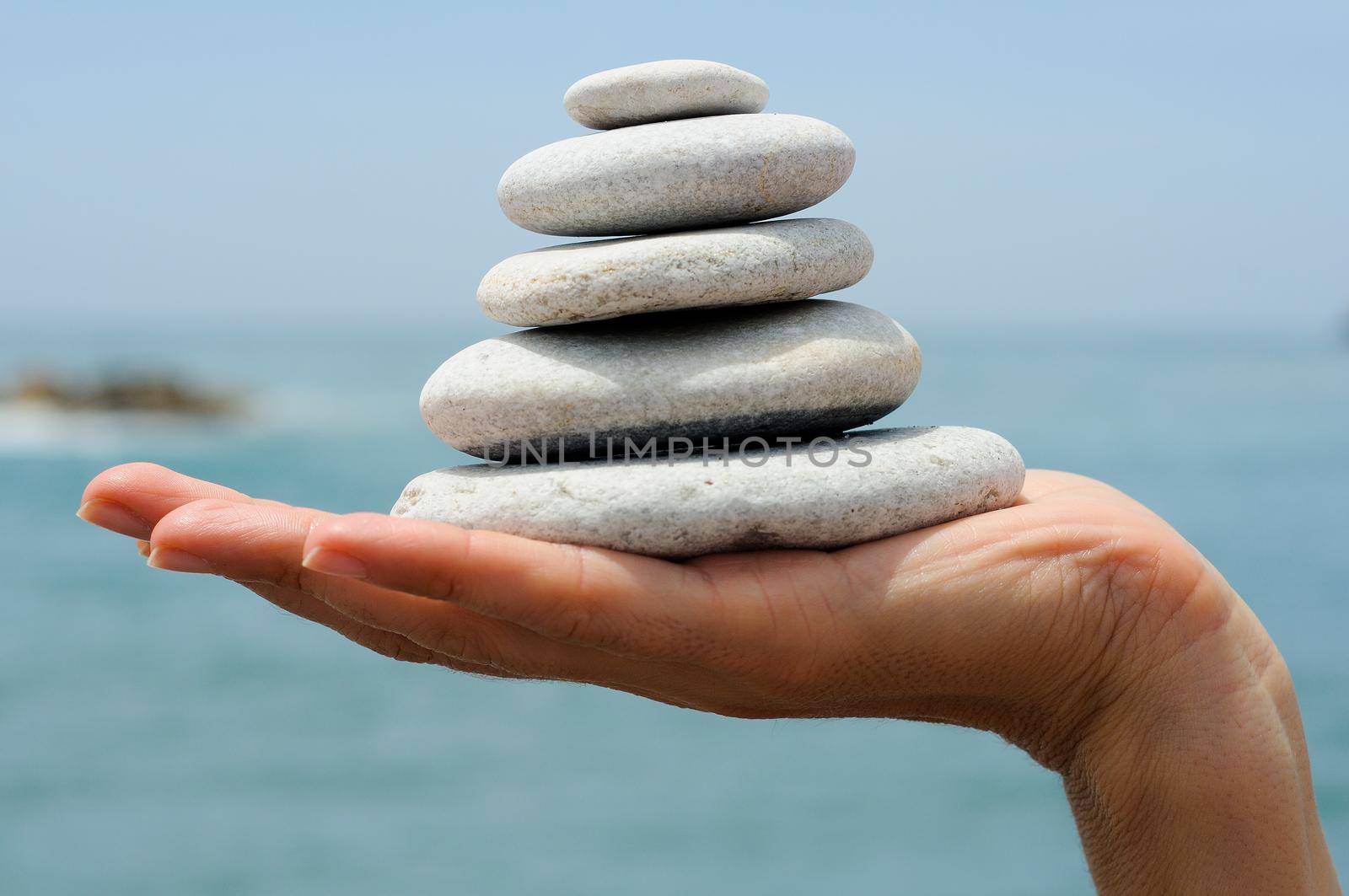 Close-up of gravel pile in woman's hands with sea background