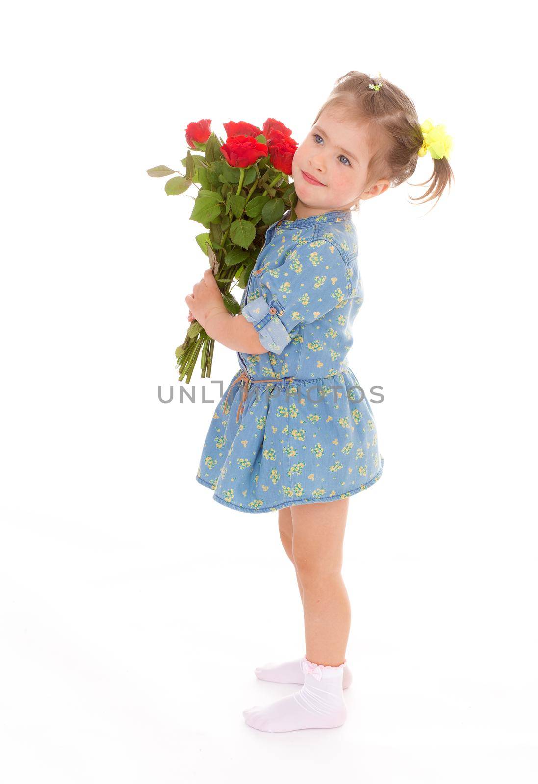 Charming girl in blue dress with a bouquet of red roses