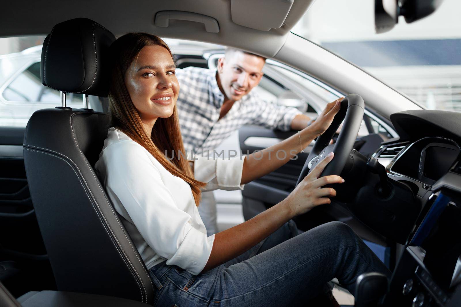 Young attractive woman looking for a new car in a car showroom