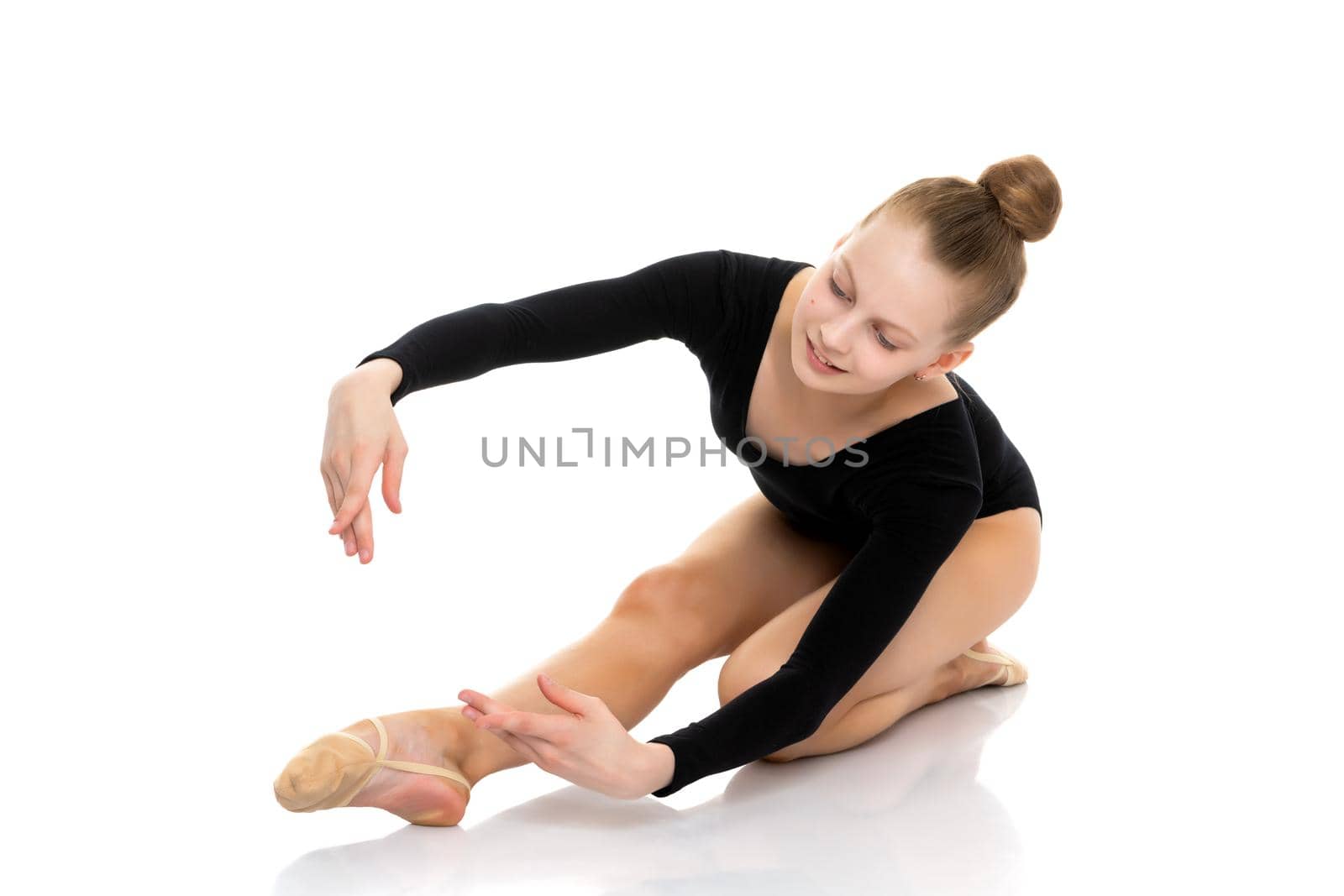 A girl gymnast performs an acrobatic element on the floor. The concept of childhood, sport, healthy lifestyle. Isolated on white background.