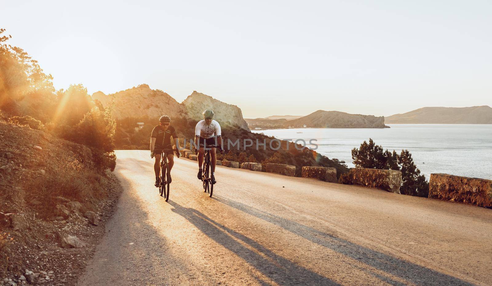 Two professional male cyclists riding their racing bicycles in the morning together on coastal road