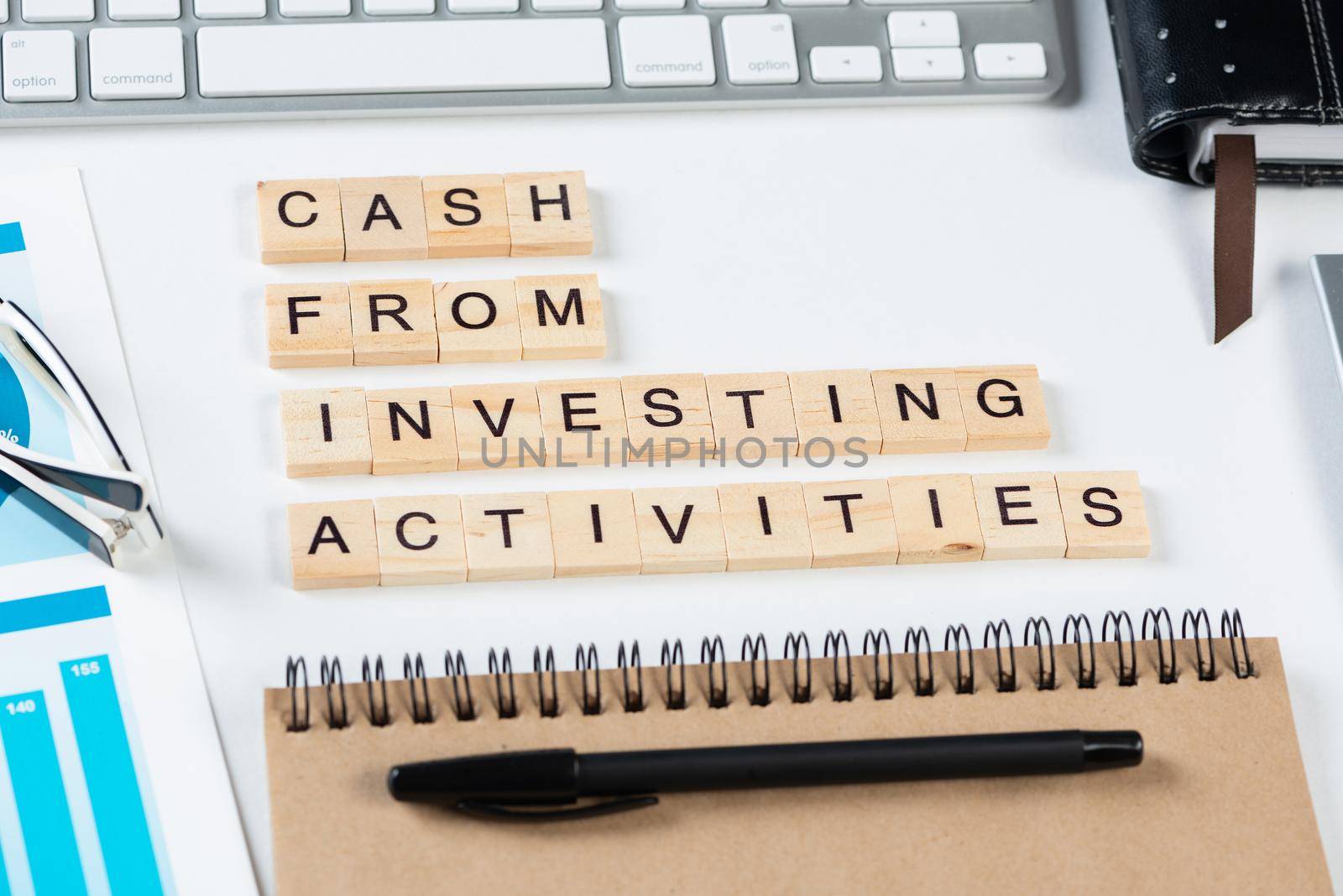 Cash from investing activities concept with letters. Still life of office workplace with supplies. Flat lay white surface with computer keyboard and notepad. Financial management and accounting.