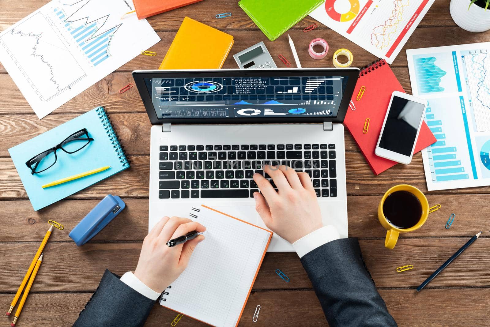 Close up businessman hands working at laptop. Top view office workplace with computer and financial documents on wooden table. Business occupation design with man in business suit sitting at desk