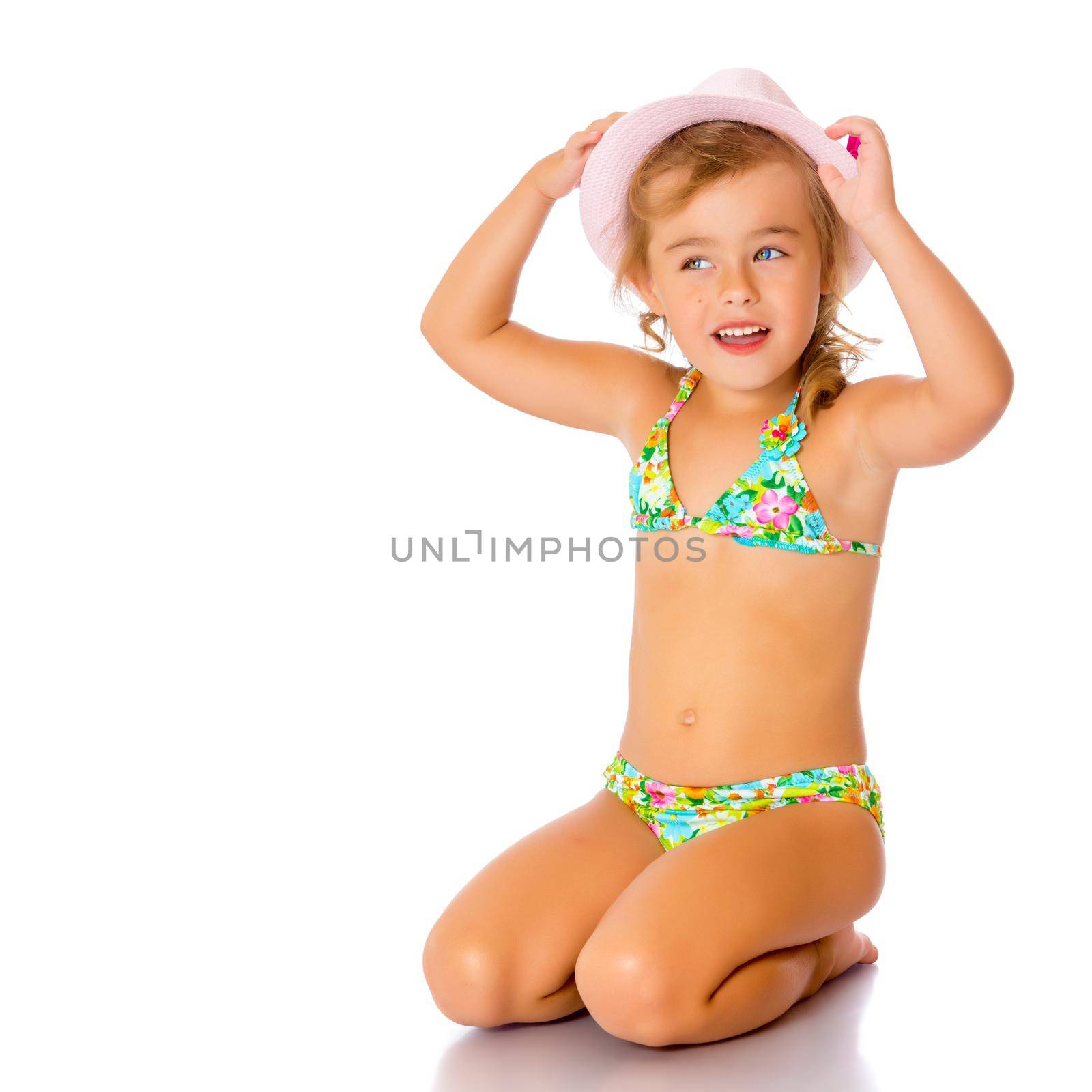 Beautiful little tanned girl in a swimsuit and a hat. The concept of summer family vacations, rest on the sea, beautiful tan. Isolated on white background.