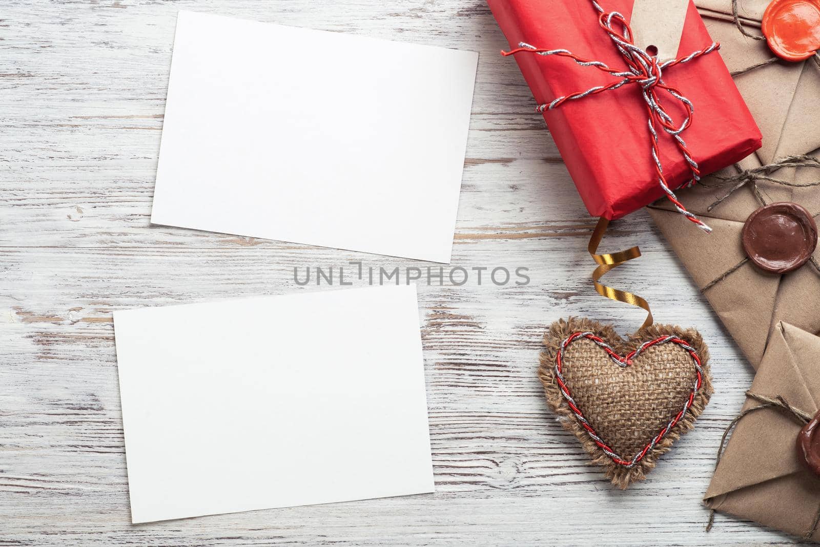 Flat lay cute composition with handmade fabric heart. White paper and retro mail envelopes on wooden table. Happy birthday or anniversary congratulation. Romantic message template with copy space