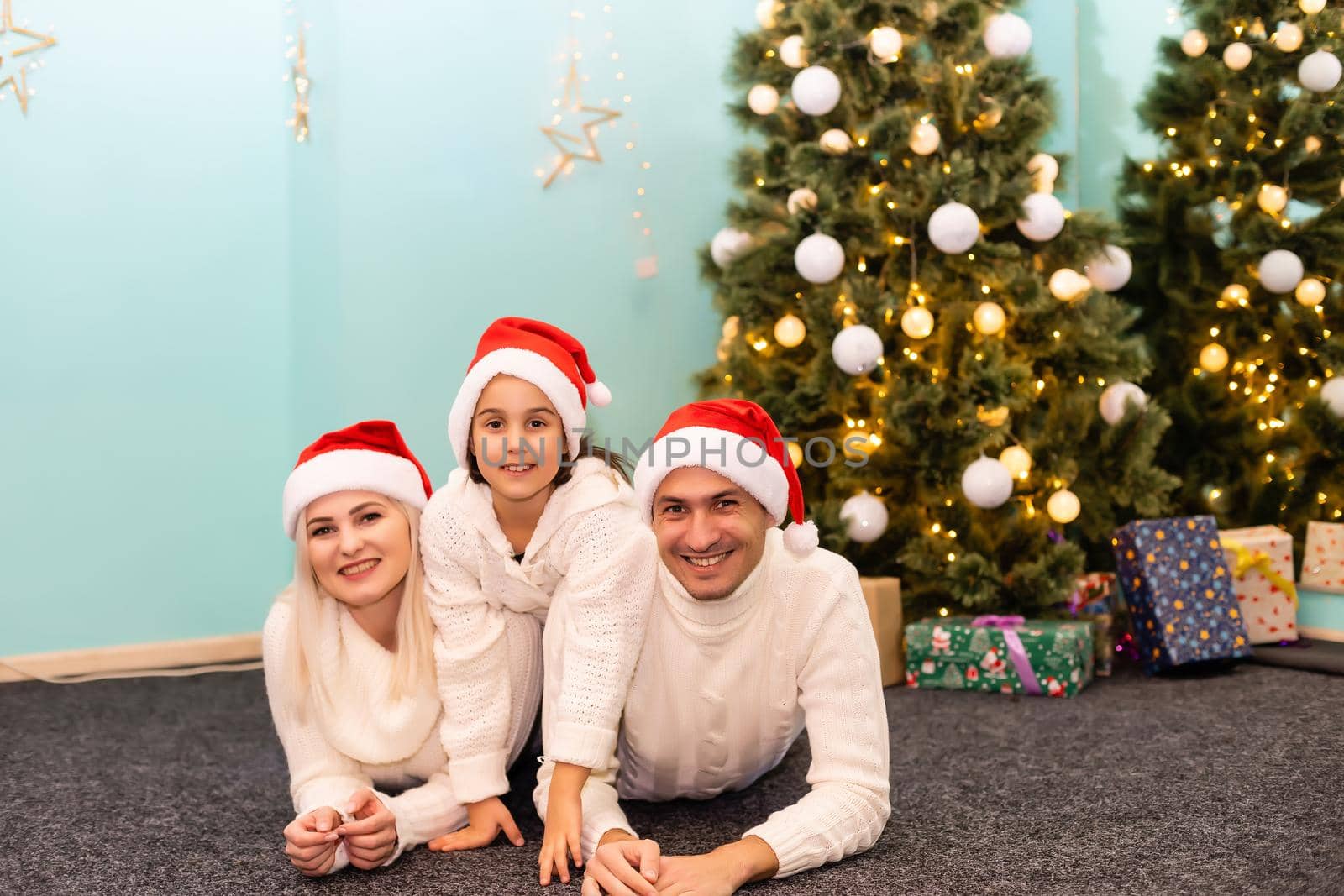 family, christmas, x-mas, winter, happiness and people concept - smiling family in santa helper hats with many gift boxes and bengal lights by Andelov13