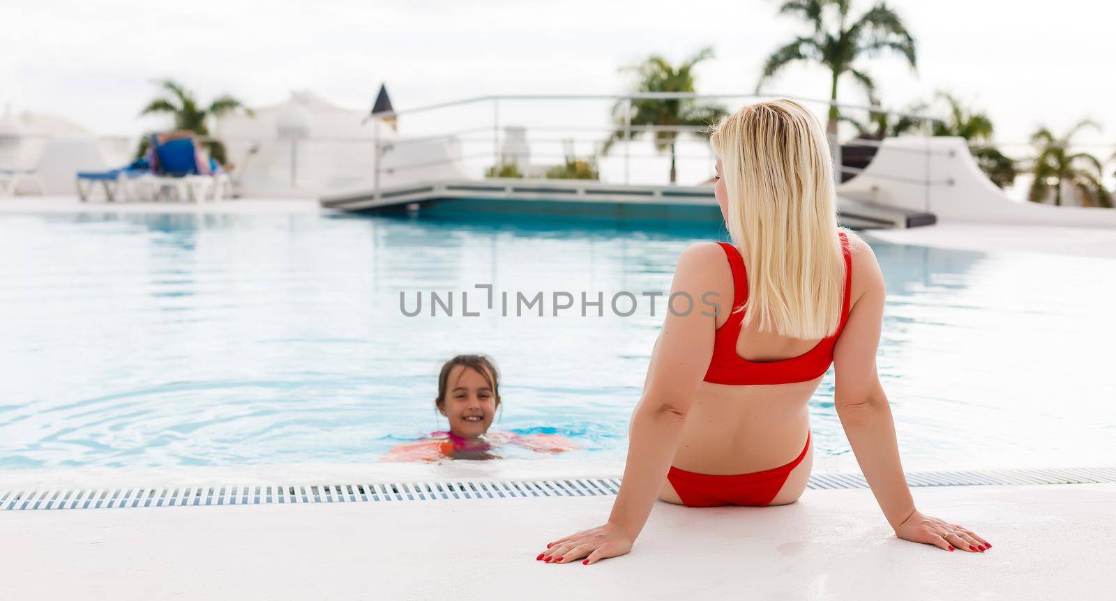 Woman enjoying vacation holidays at luxurious beachfront hotel resort with swimming pool and tropical lansdcape near the beach by Andelov13