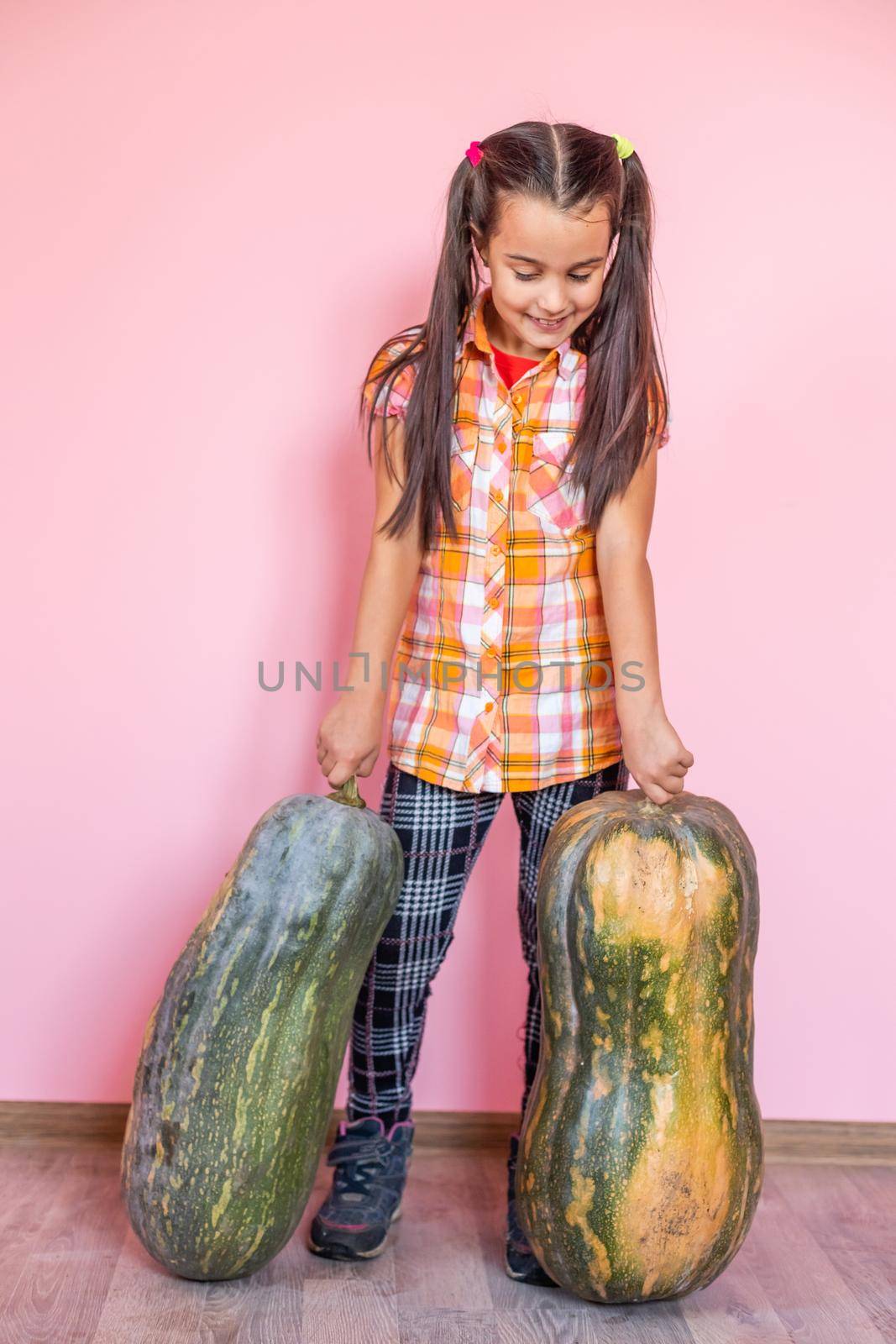 Beautiful girl with pumpkin on a pink background