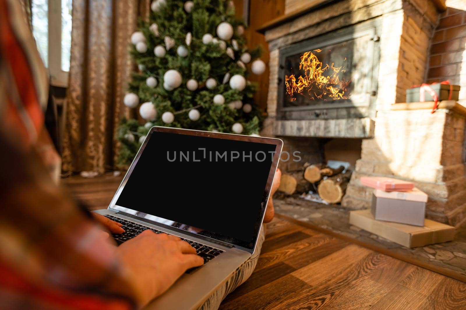 Happy woman looking in laptop in front of Christmas tree
