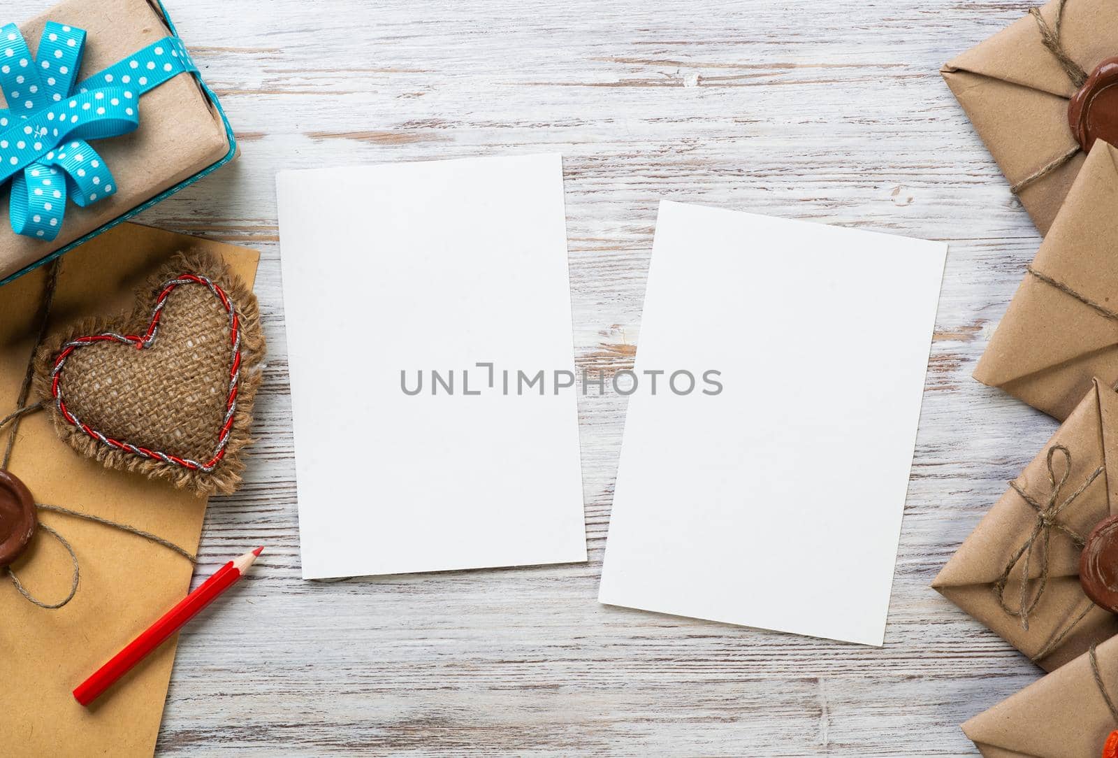 Flat lay cute composition with handmade fabric heart. White paper and retro mail envelopes on wooden table. Happy birthday or anniversary congratulation. Romantic message template with copy space