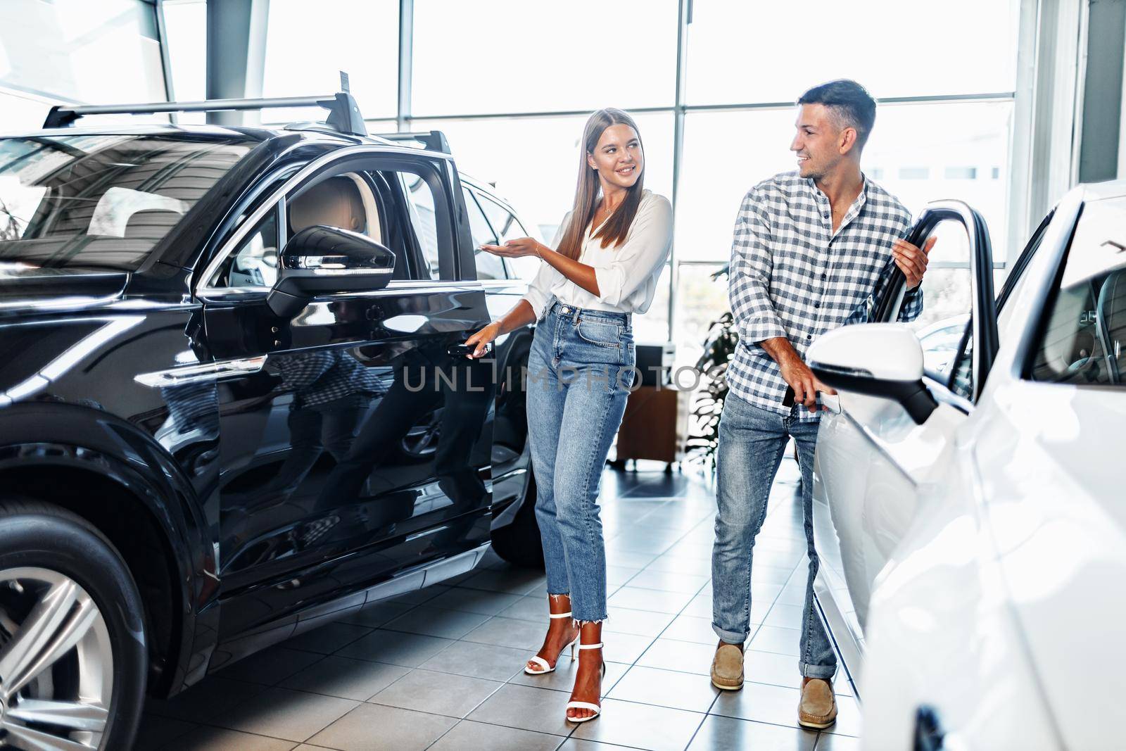 Young happy couple just bought a new car in a dealership showroom