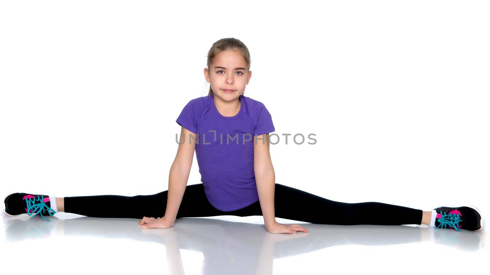 A little girl performs a gymnastic twine. The concept of fitness and sports. Isolated on white background.