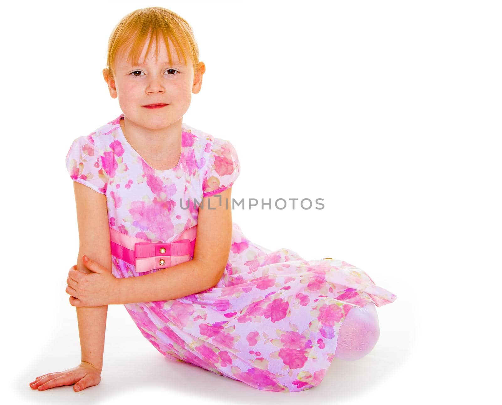 Sits leaning on hand a small charming girl. Isolated on white background