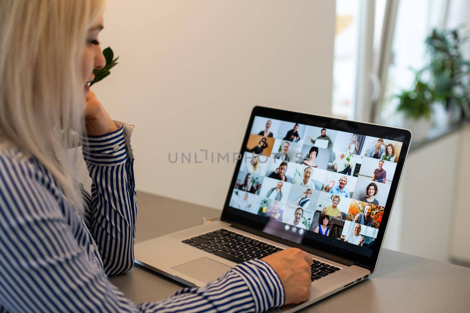 Back view of business woman talking to her colleagues about plan in video conference. Multiethnic business team using laptop for a online meeting in video call. Group of people smart working from home