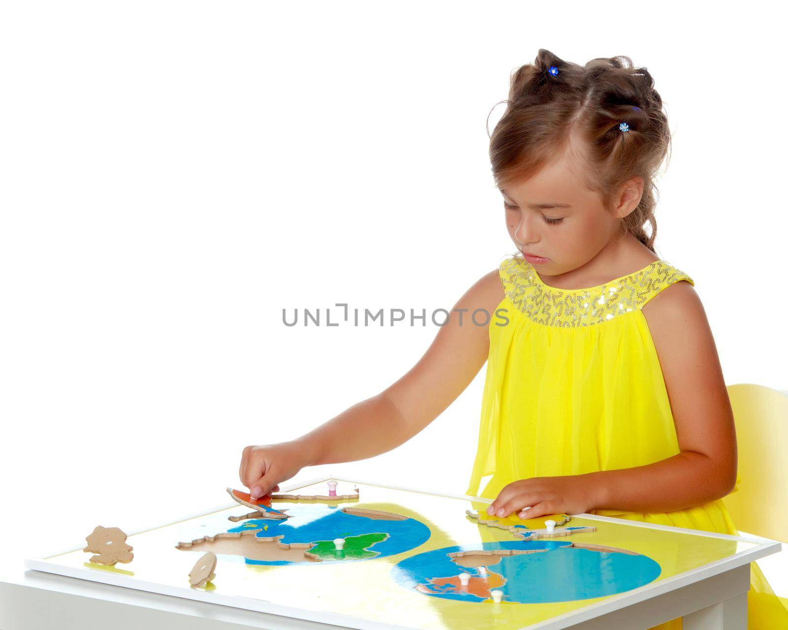 A little girl in Montessori kindergarten sits at a table and studies Montessori stuff. The concept of school and preschool education, harmonious development of the child. Isolated on white background.