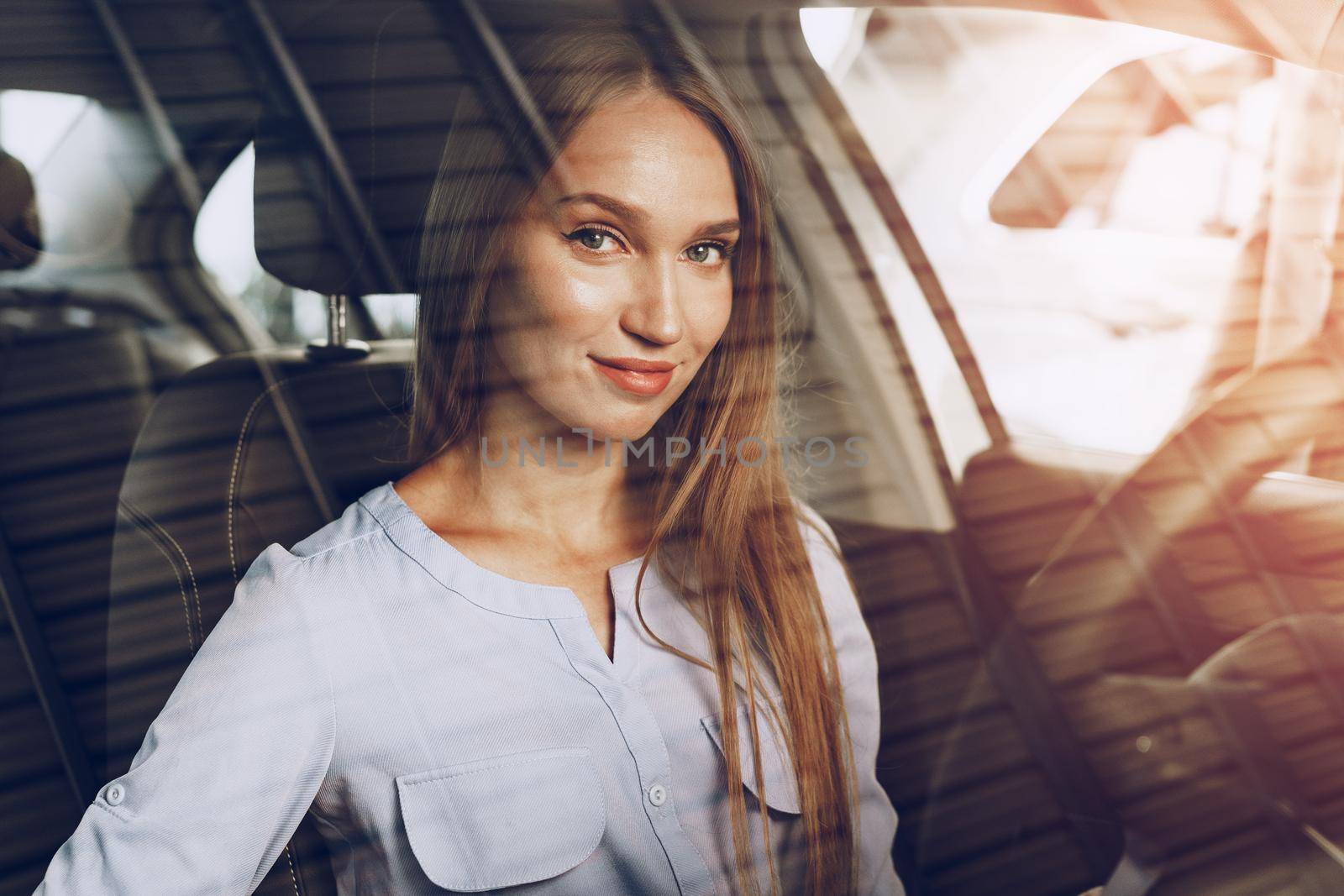 Attractive young woman sitting in new car in showroom close up