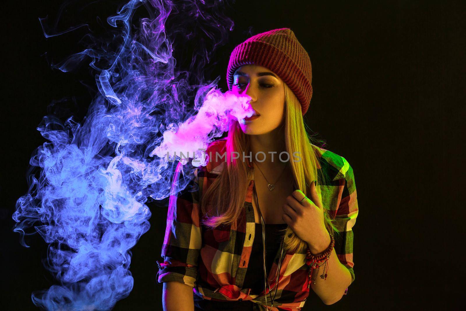 Vaping girl. Young hipster woman vape e-cig on studio on black background. Hip-hop style. Close up. Vapor concept. Vaping e-Cigarette.