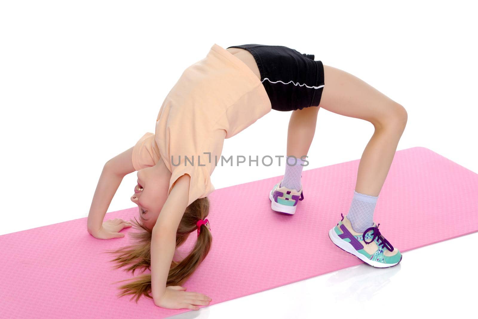 A little girl gymnast performs a bridge. The concept of childhood, sport, healthy lifestyle. Isolated on white background.
