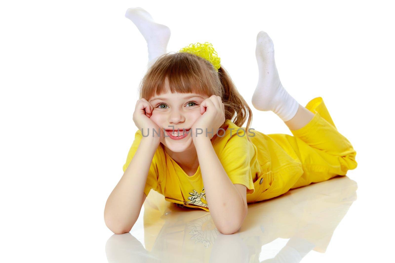 Girl with a short bangs on her head and bright yellow overalls.She crouched down on the white advertising banner.