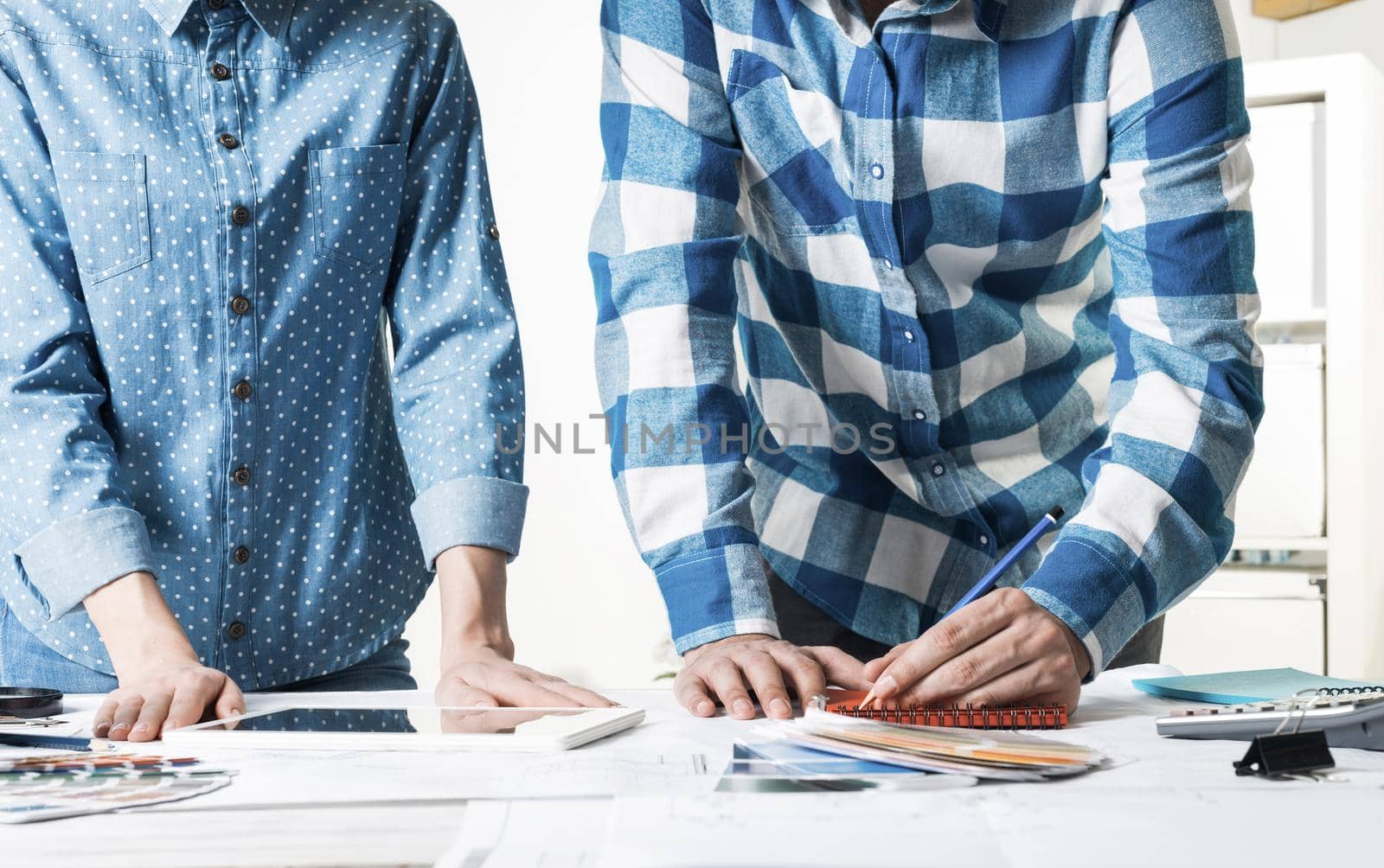 Designers working with color swatches and tablet computer at desk. Interior design, architectural decoration and renovation. Brainstorm, teamwork and creativity. Decorator workplace in design agency