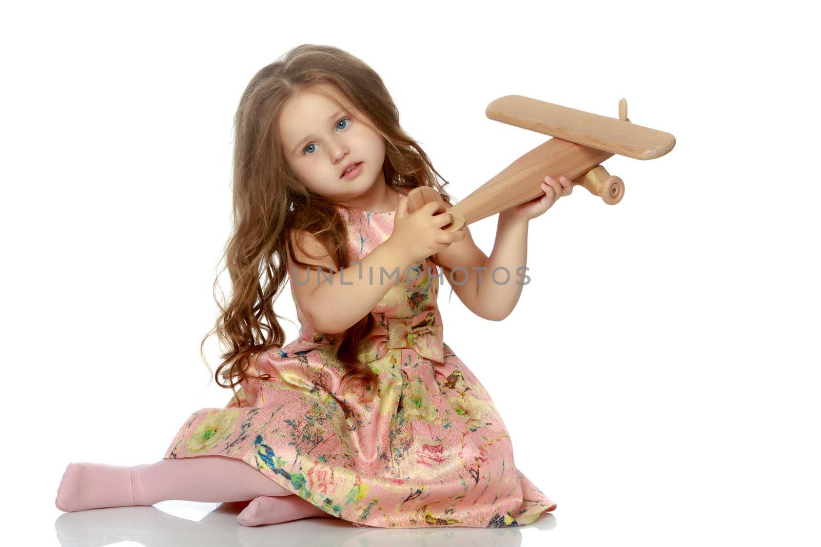 Little girl with a plane in her hand. The concept of a dream of long journeys. Isolated on white background.