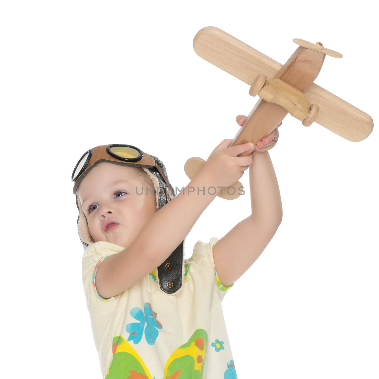 Little girl in helmet pilot with wooden plane in hand. The concept of family happiness, the embodiment of a dream, a love of travel. Isolated on white background.